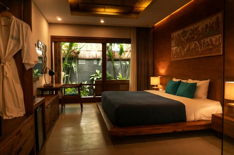 Hotel bedroom with a king bed, wooden furnishings and a garden view